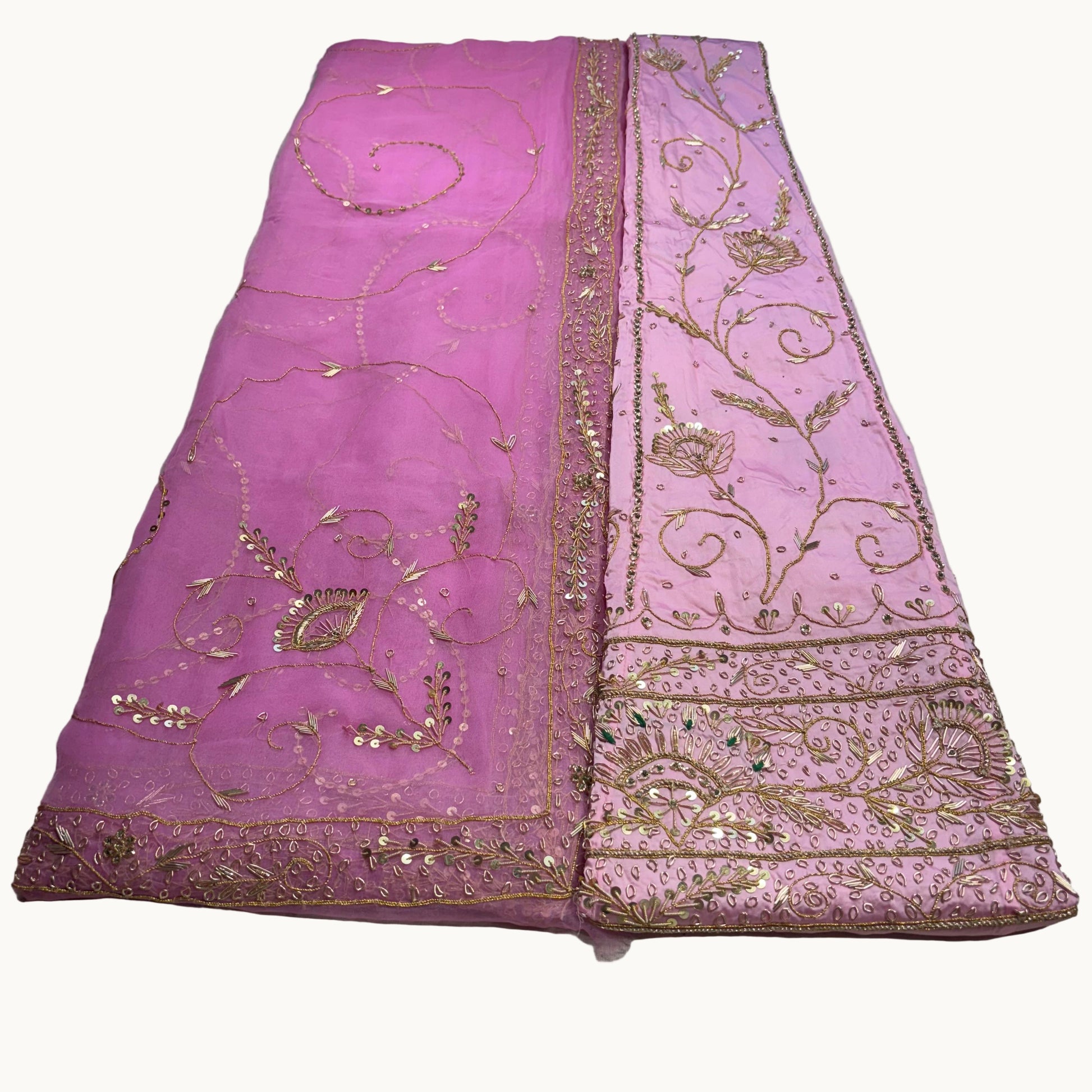 Pink embroidered fabric with gold detailing on a light gray background