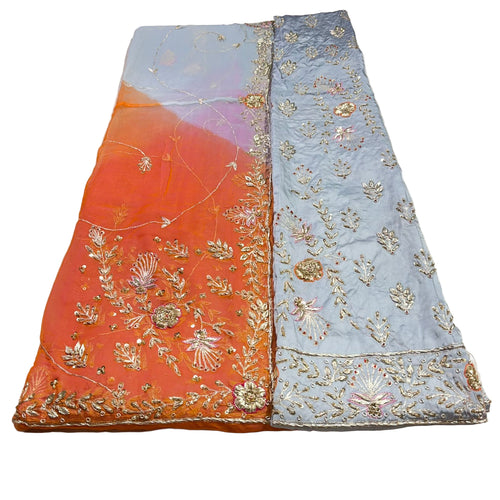 Two embroidered fabric panels, one orange and one light blue, on a plain background.