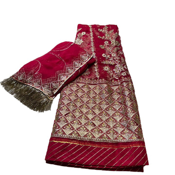 Red embroidered fabric with gold patterns on a light gray surface