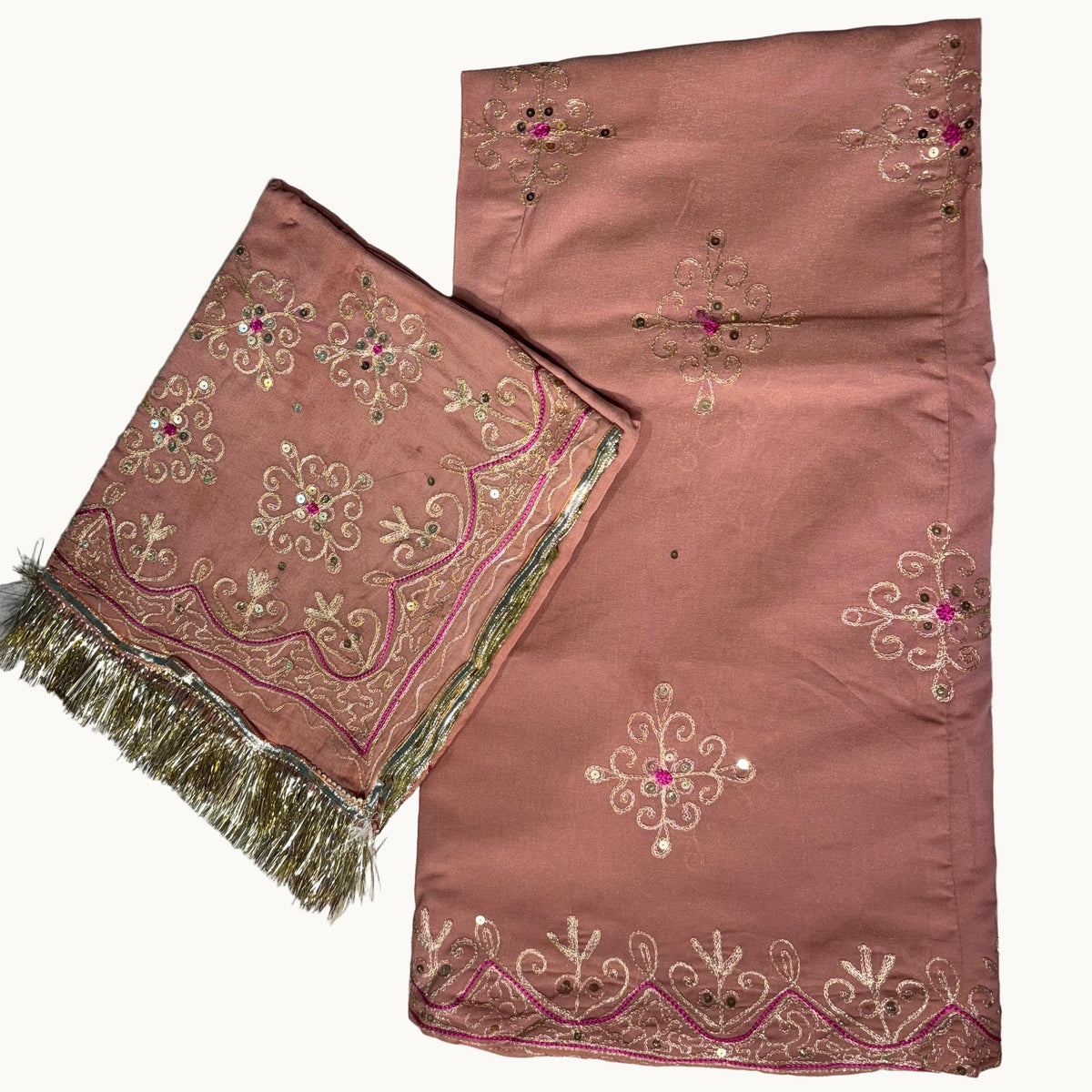 Pink fabric with intricate gold and red embroidery on a light gray background