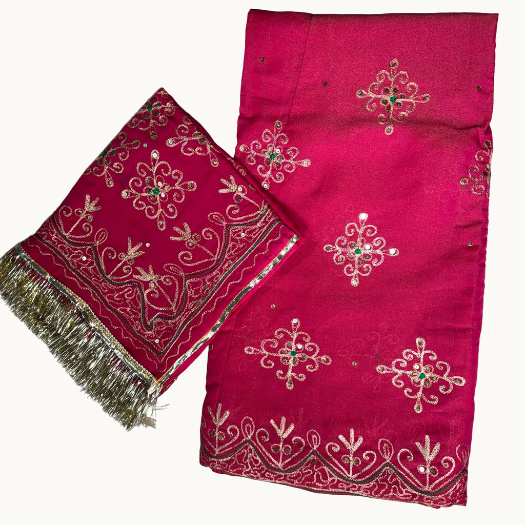 Pink fabric with intricate white embroidery on a light gray background