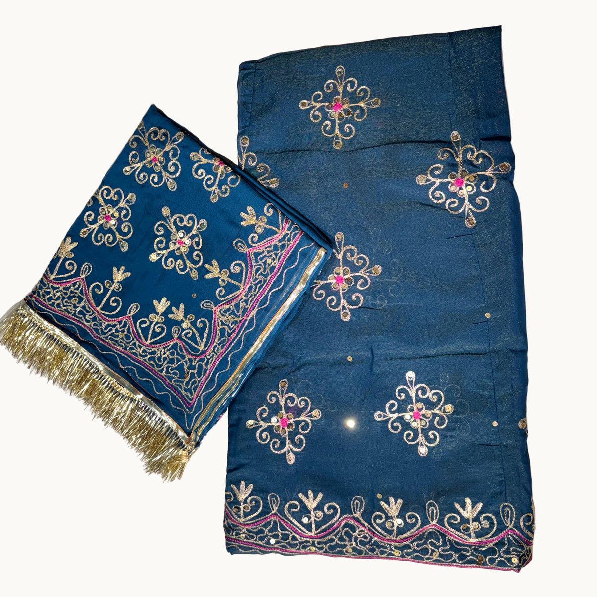 Blue embroidered fabric with gold and pink details on a light gray background