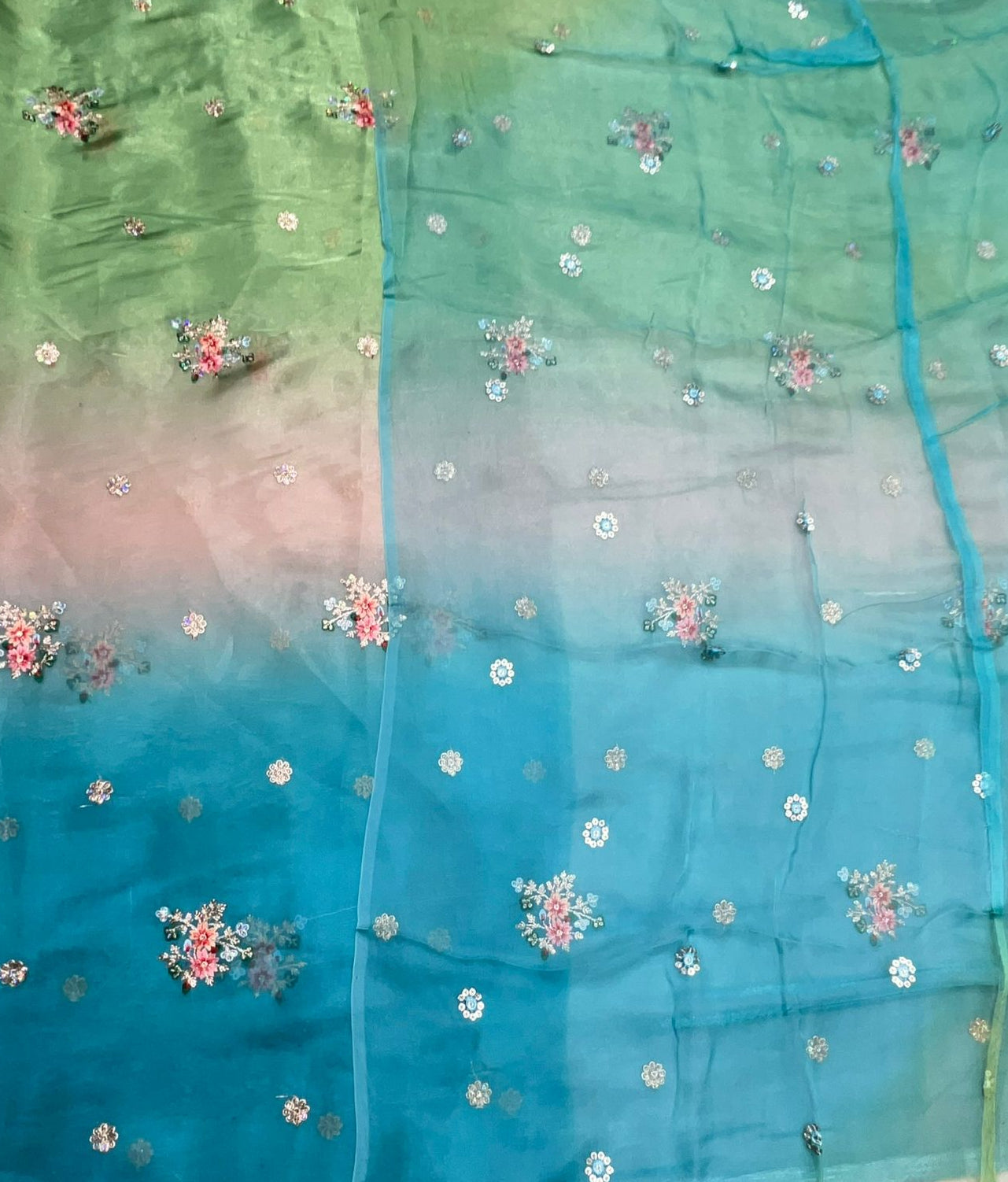 Gradient fabric with floral embroidery in green, blue, and pink.