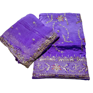 Purple fabric with intricate gold embroidery on a light gray background