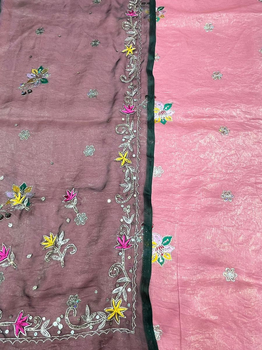 Two pink fabric pieces with floral embroidery on a light blue background