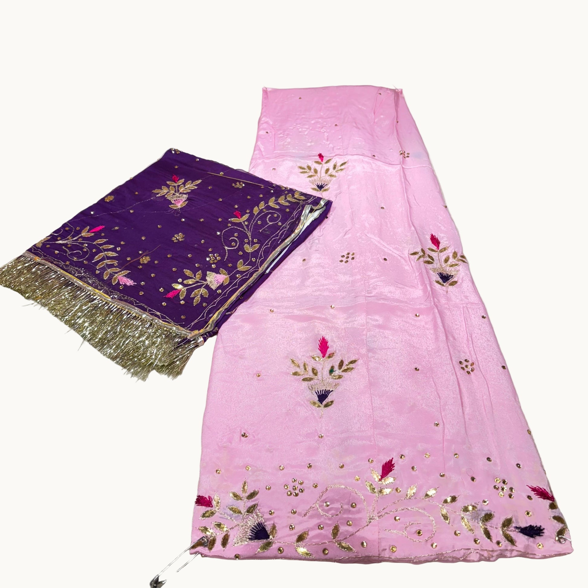 Pink embroidered fabric with a purple fabric with gold embroidery on a light gray background