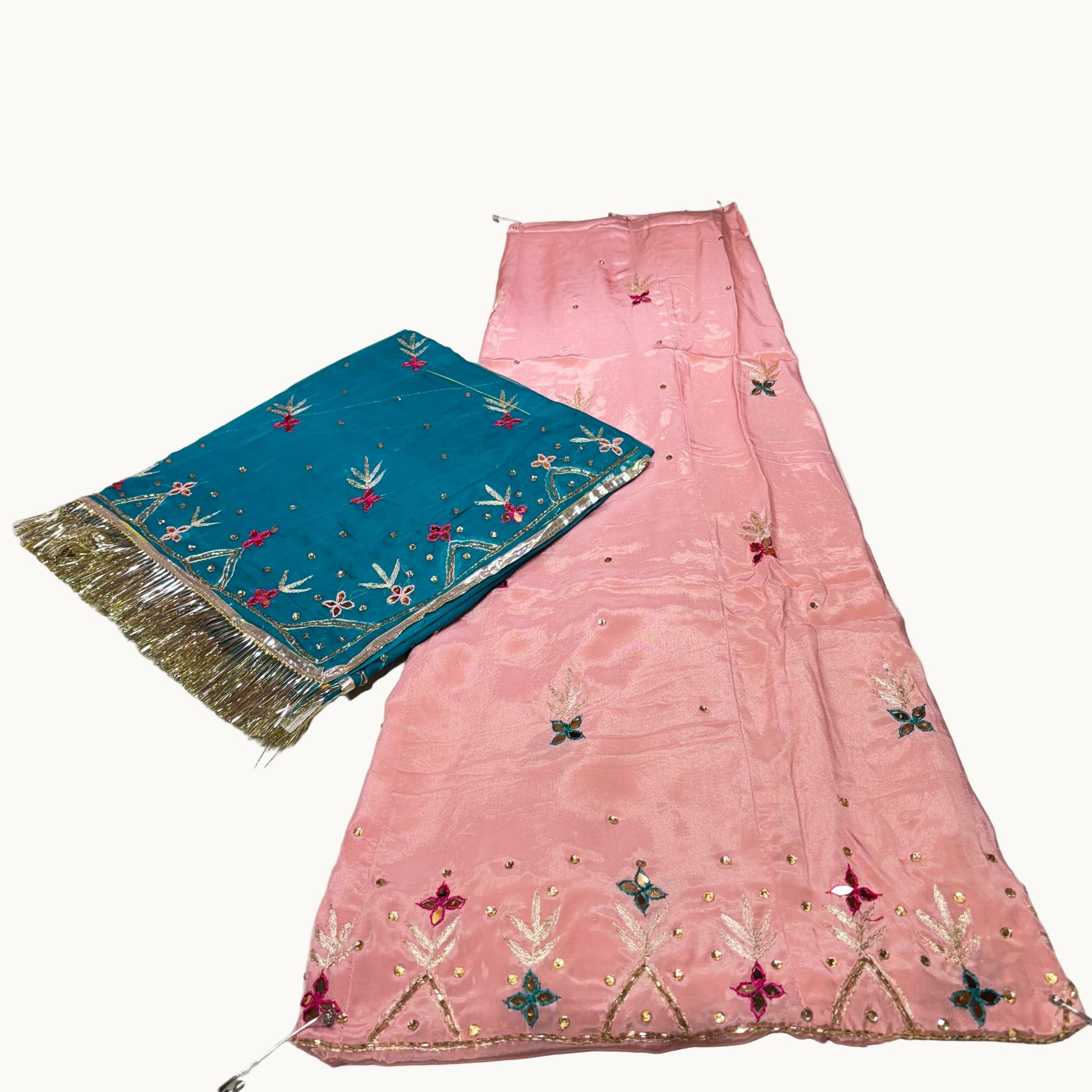 Pink embroidered fabric and blue scarf on a white surface