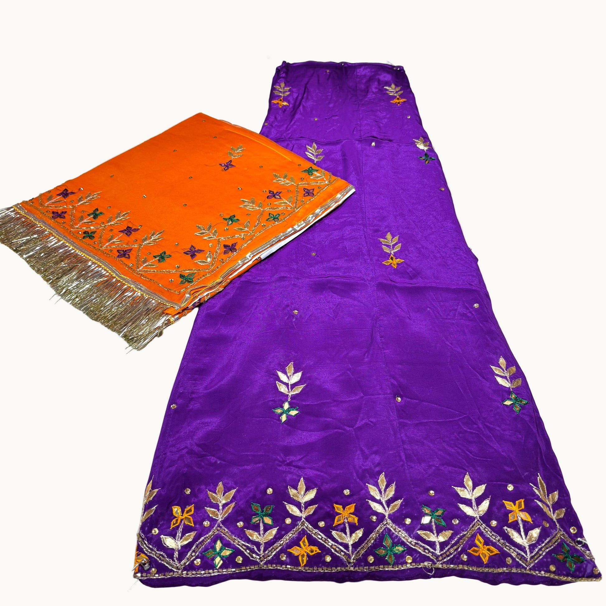 Purple fabric with floral embroidery and orange fabric with gold fringe on a white background