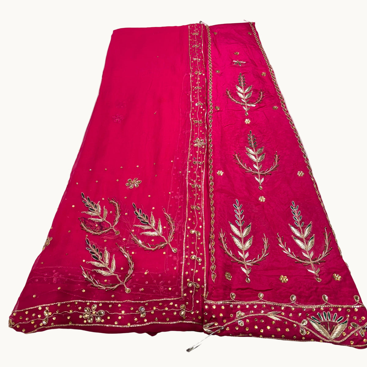 Red embroidered fabric with gold patterns on a light gray surface