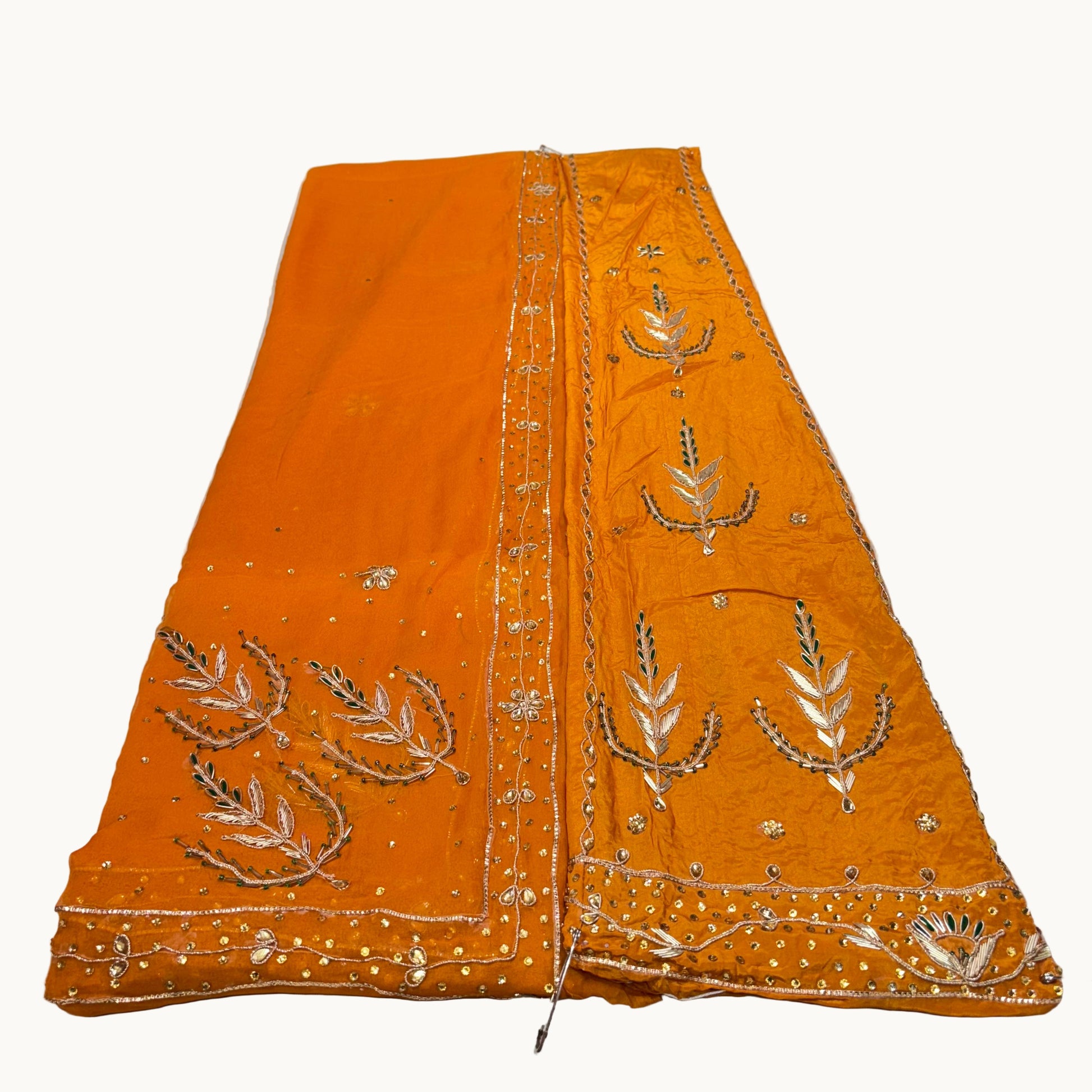Orange fabric with intricate silver embroidery on a white background