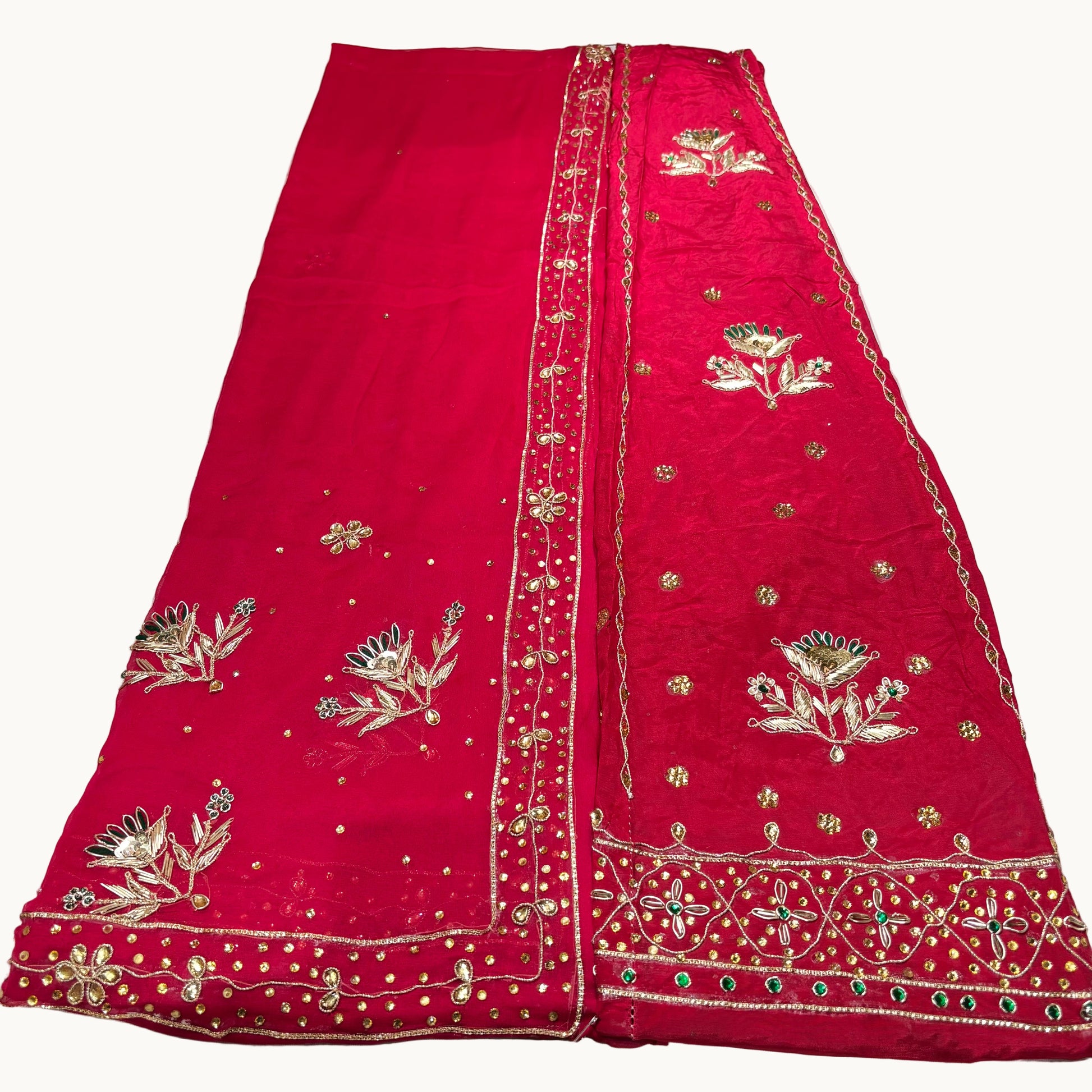 Red embroidered fabric with gold and green details on a white background