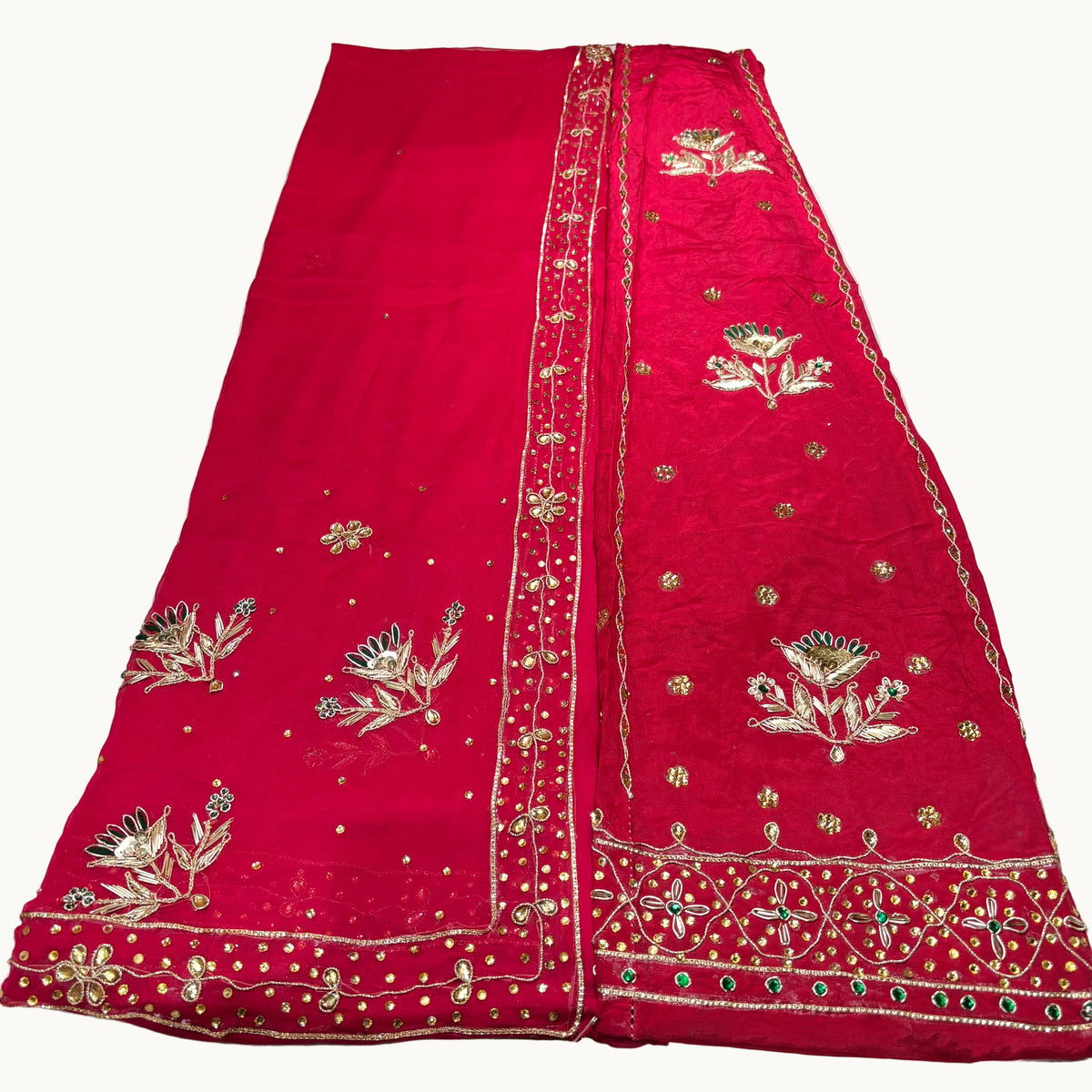 Red embroidered fabric with gold and green details on a white background