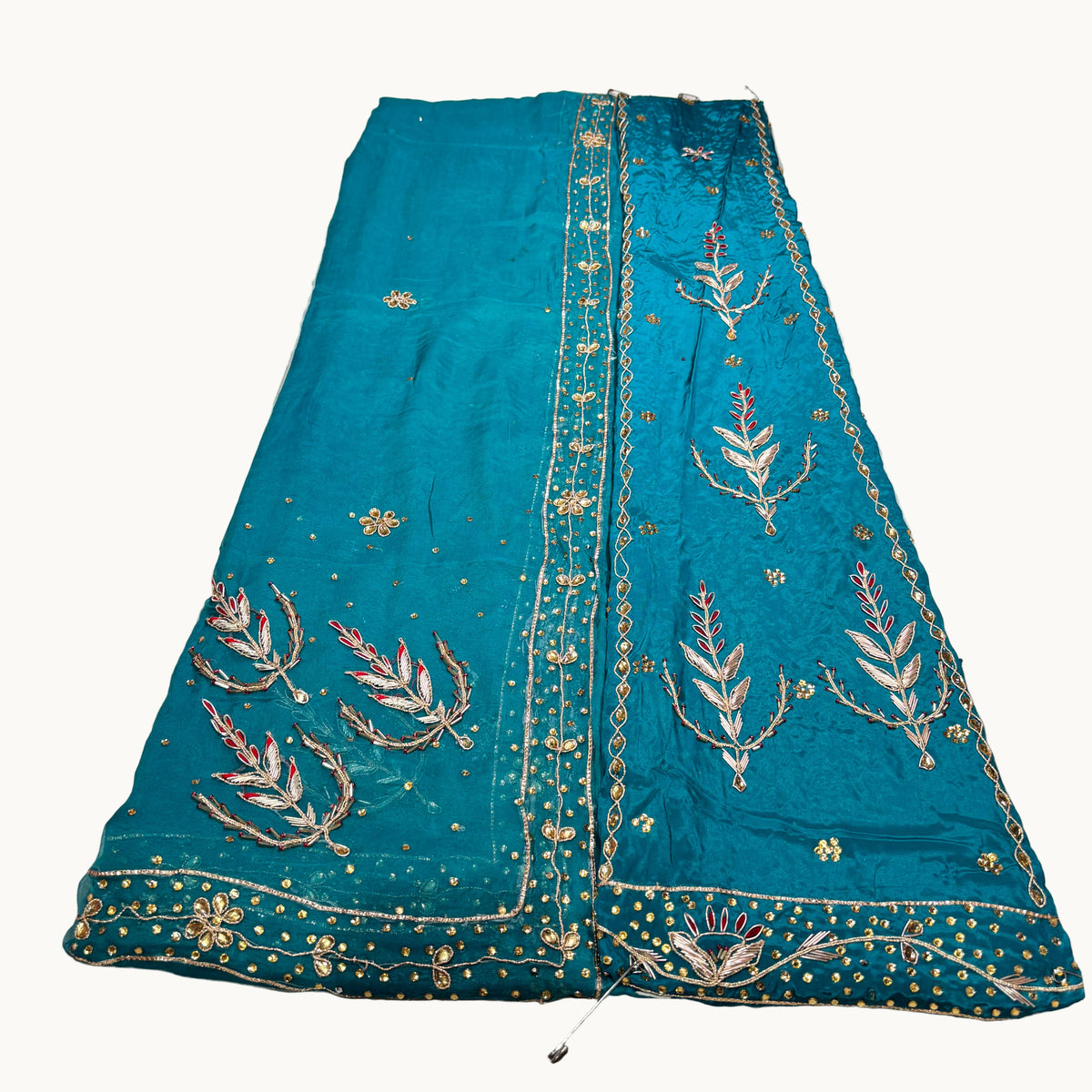 Teal embroidered fabric on a light gray background