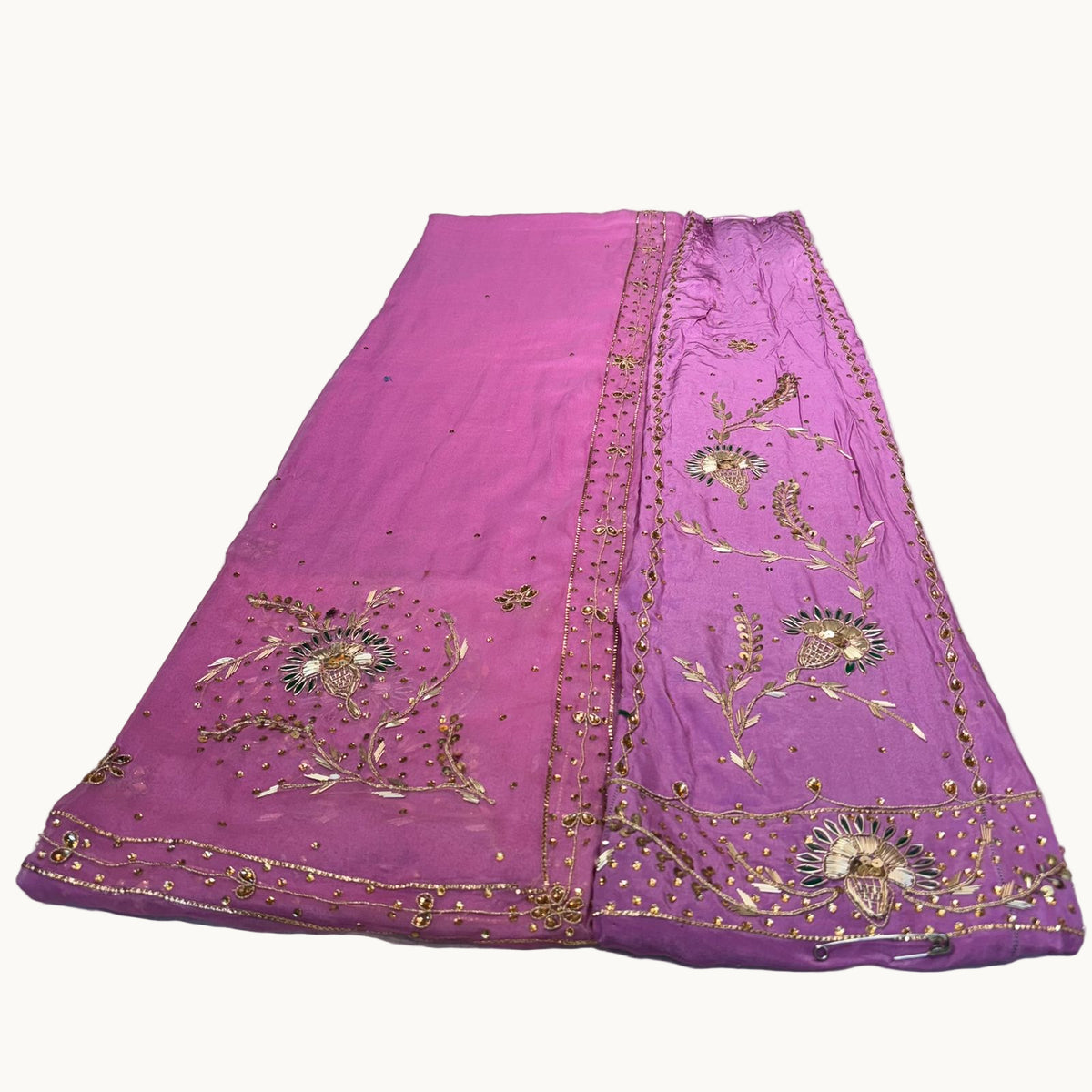 Purple fabric with gold embroidery on a white surface
