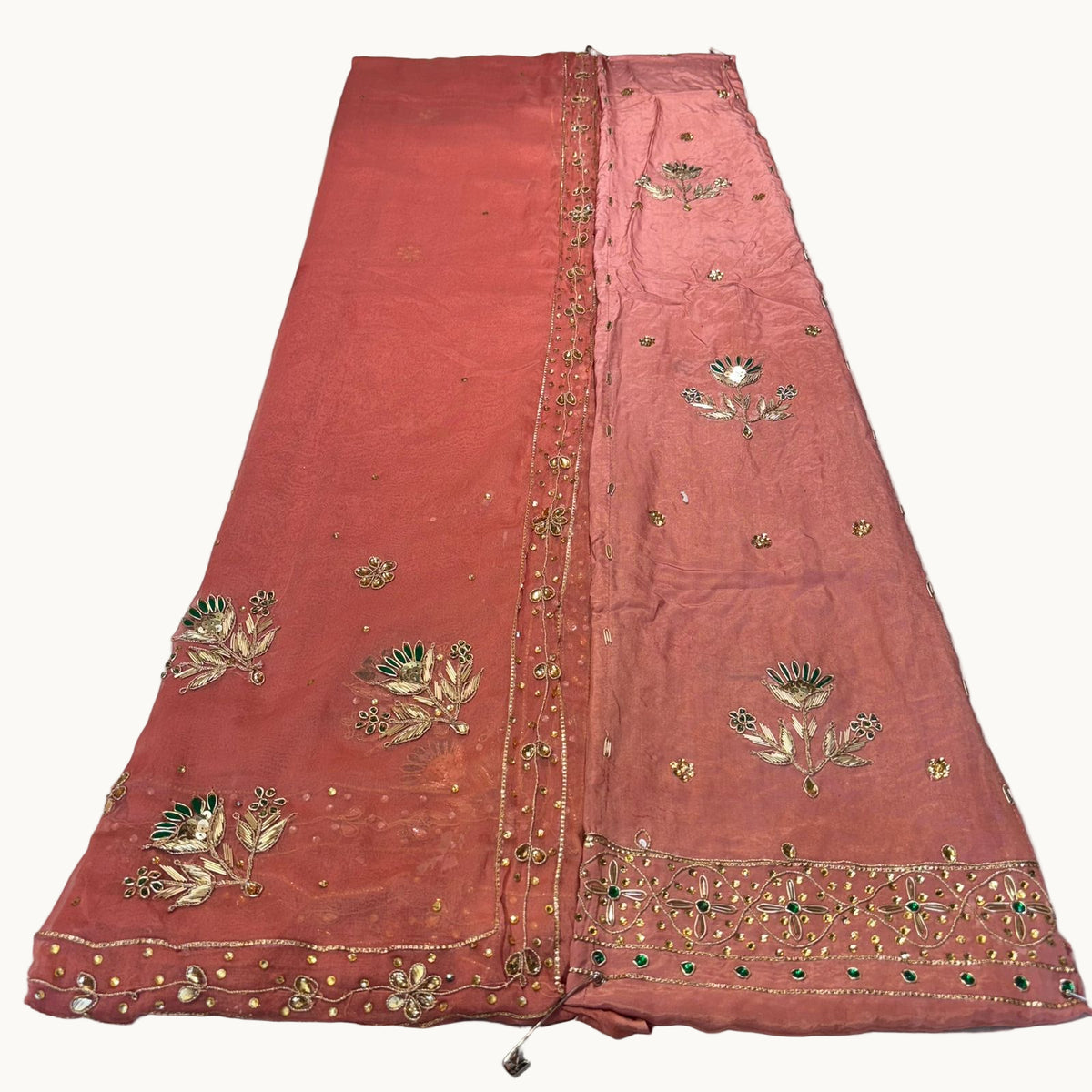 Embroidered fabric with gold and green patterns on a white background