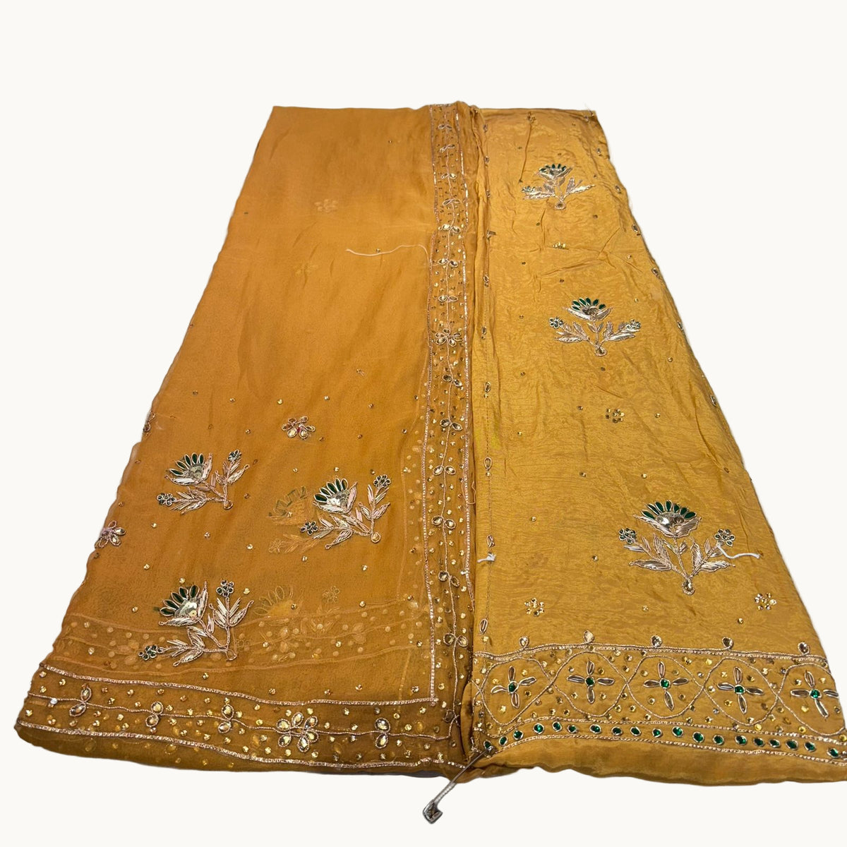 Mustard yellow fabric with intricate silver embroidery on a white background