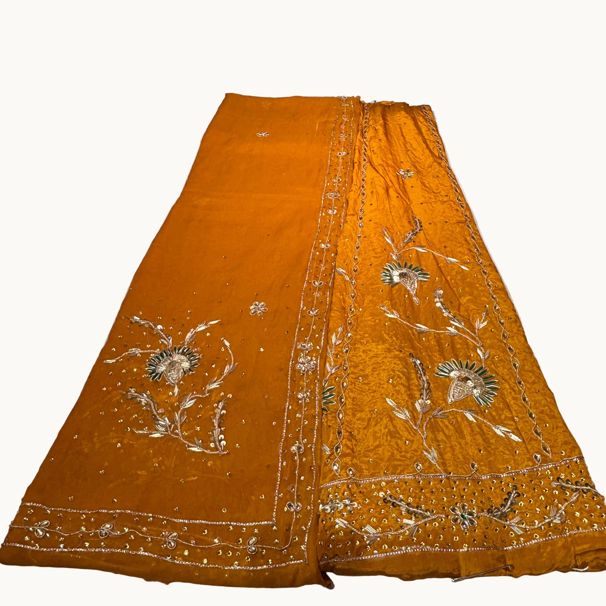 Orange fabric with intricate silver embroidery on a white surface