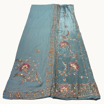 Teal fabric with floral embroidery on a light gray background