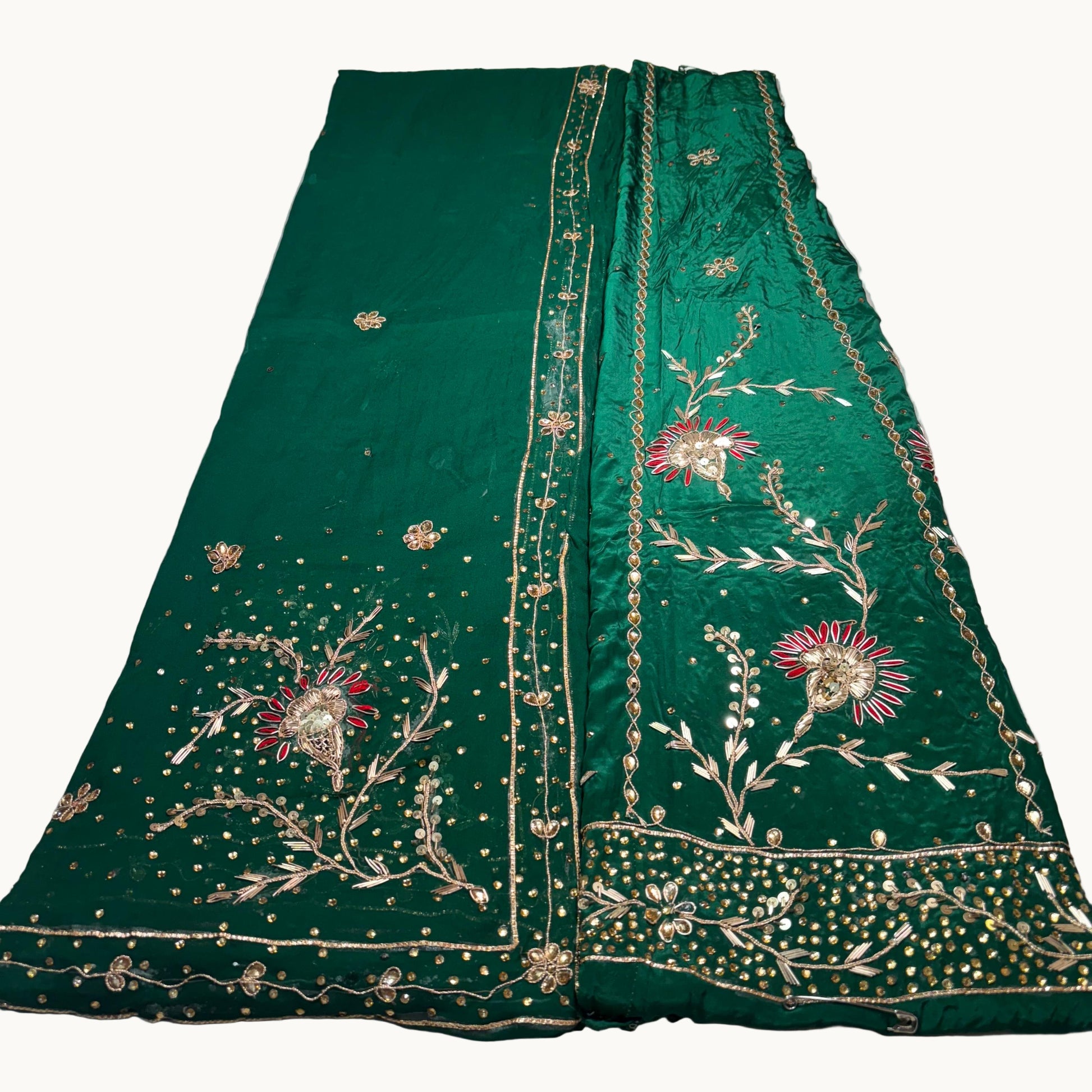 Green embroidered fabric with floral patterns on a white surface