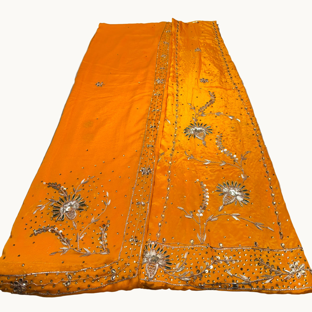 Orange fabric with intricate silver embroidery on a light gray surface