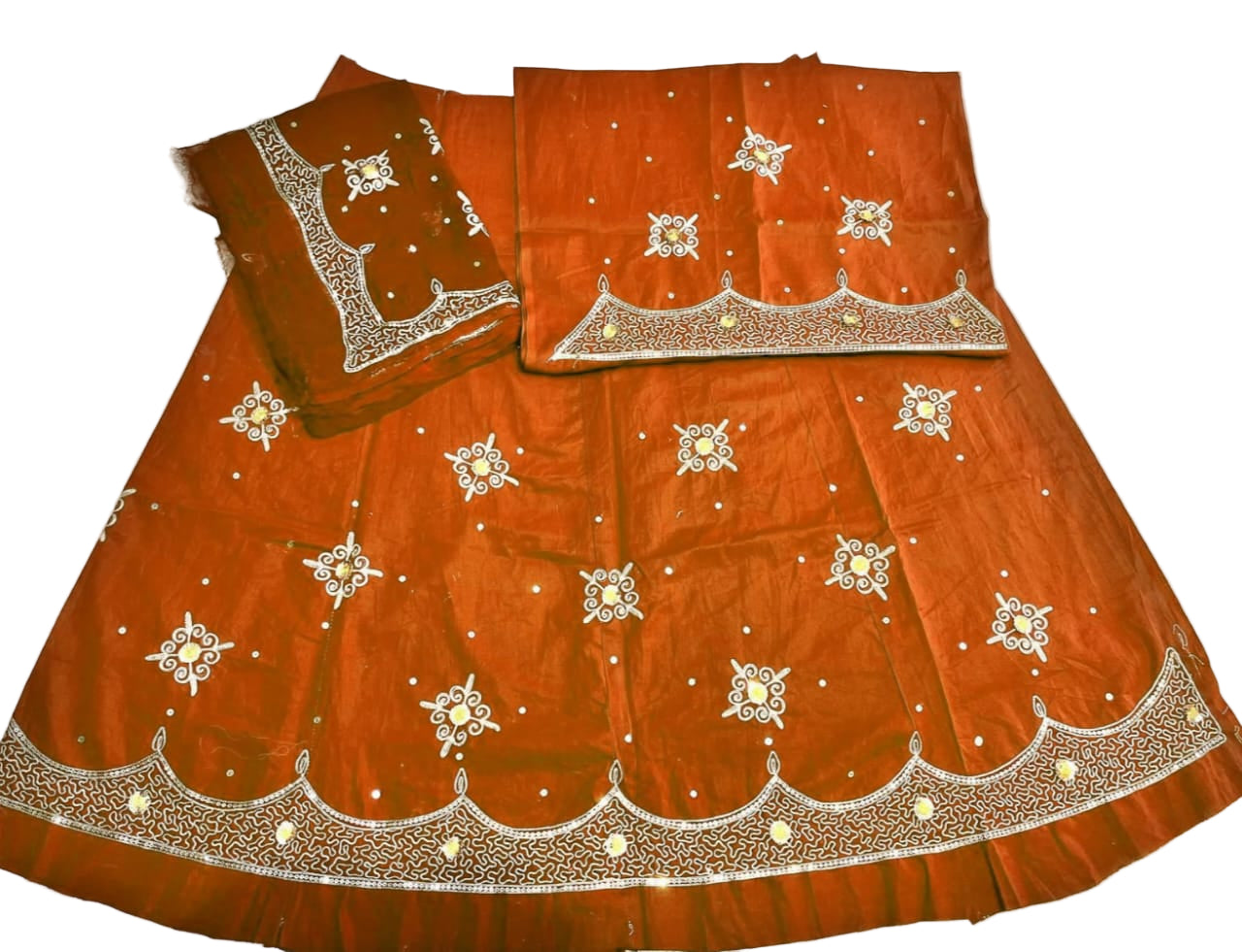 Orange traditional outfit with intricate white embroidery on a white background