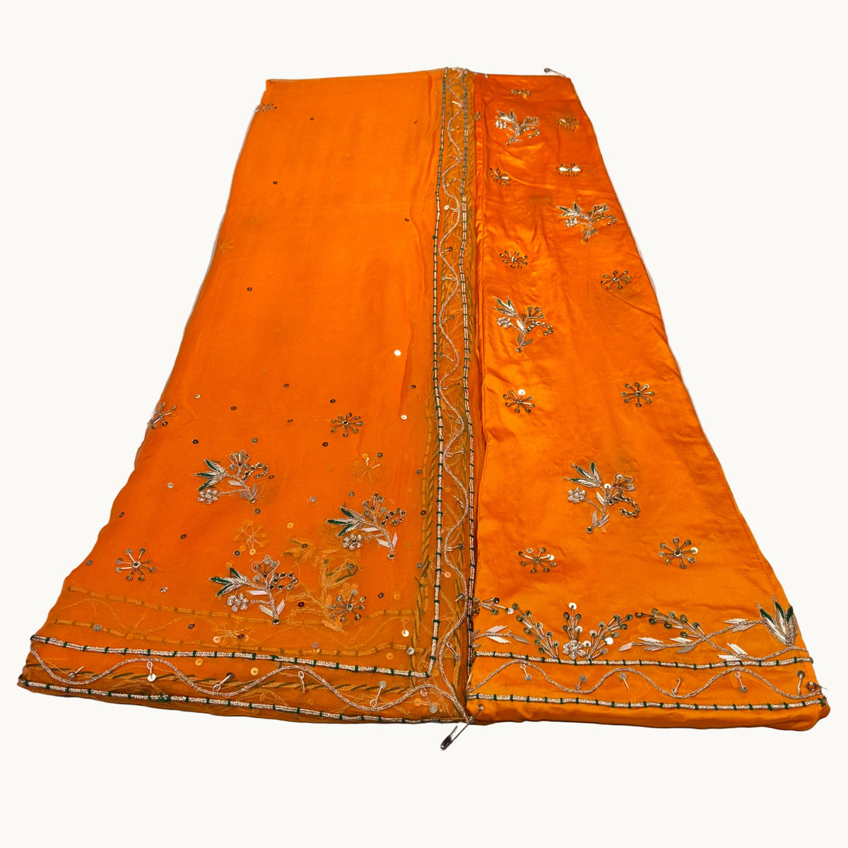 Orange fabric with gold embroidery on a light gray surface