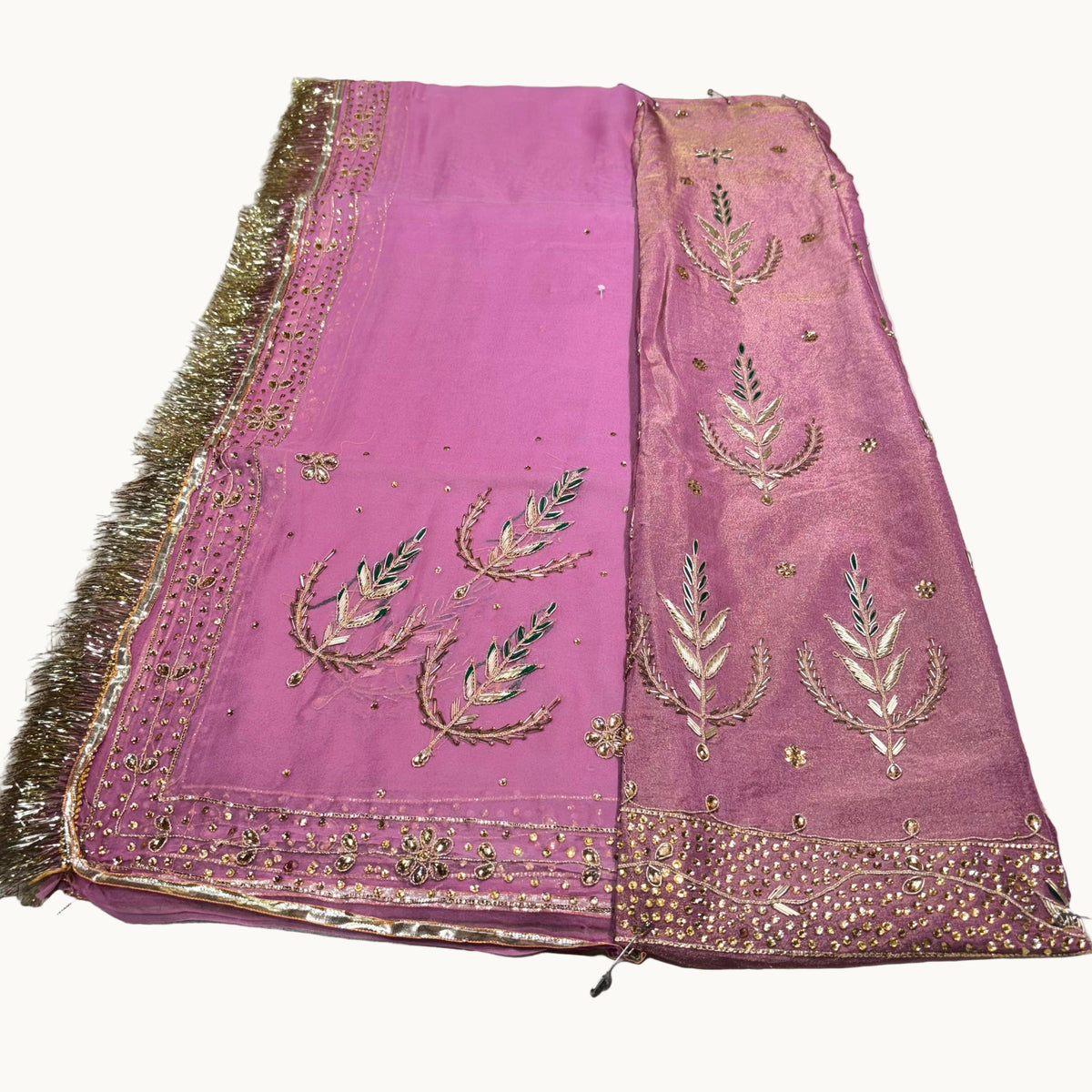 Pink fabric with gold embroidery and tassels on a white background