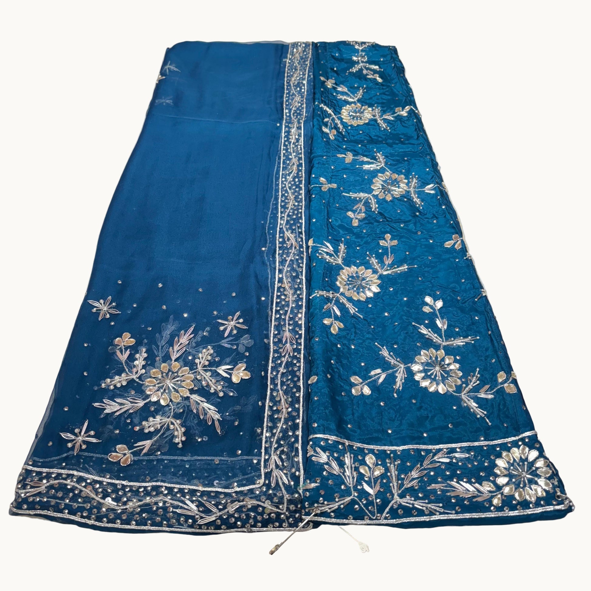 Blue fabric with floral embroidery on a light gray surface