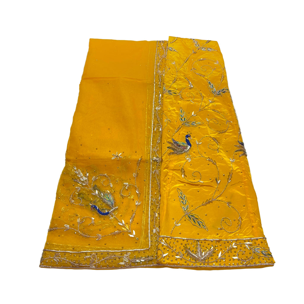 Yellow embroidered fabric with peacock designs on a white background