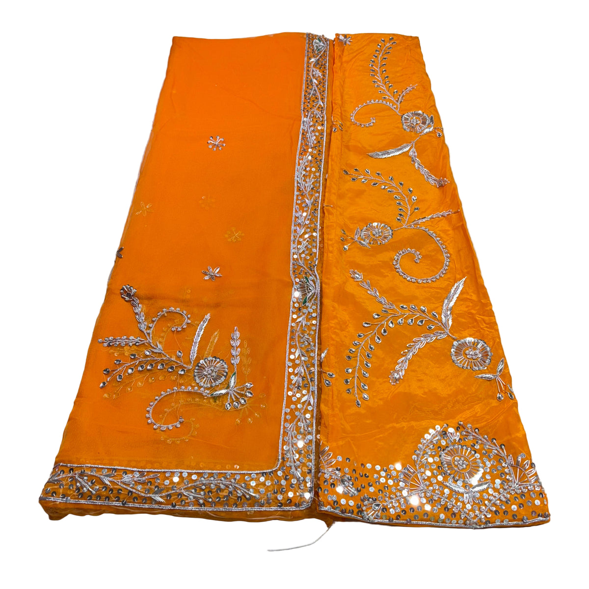 Orange fabric with silver embroidery on a light gray background