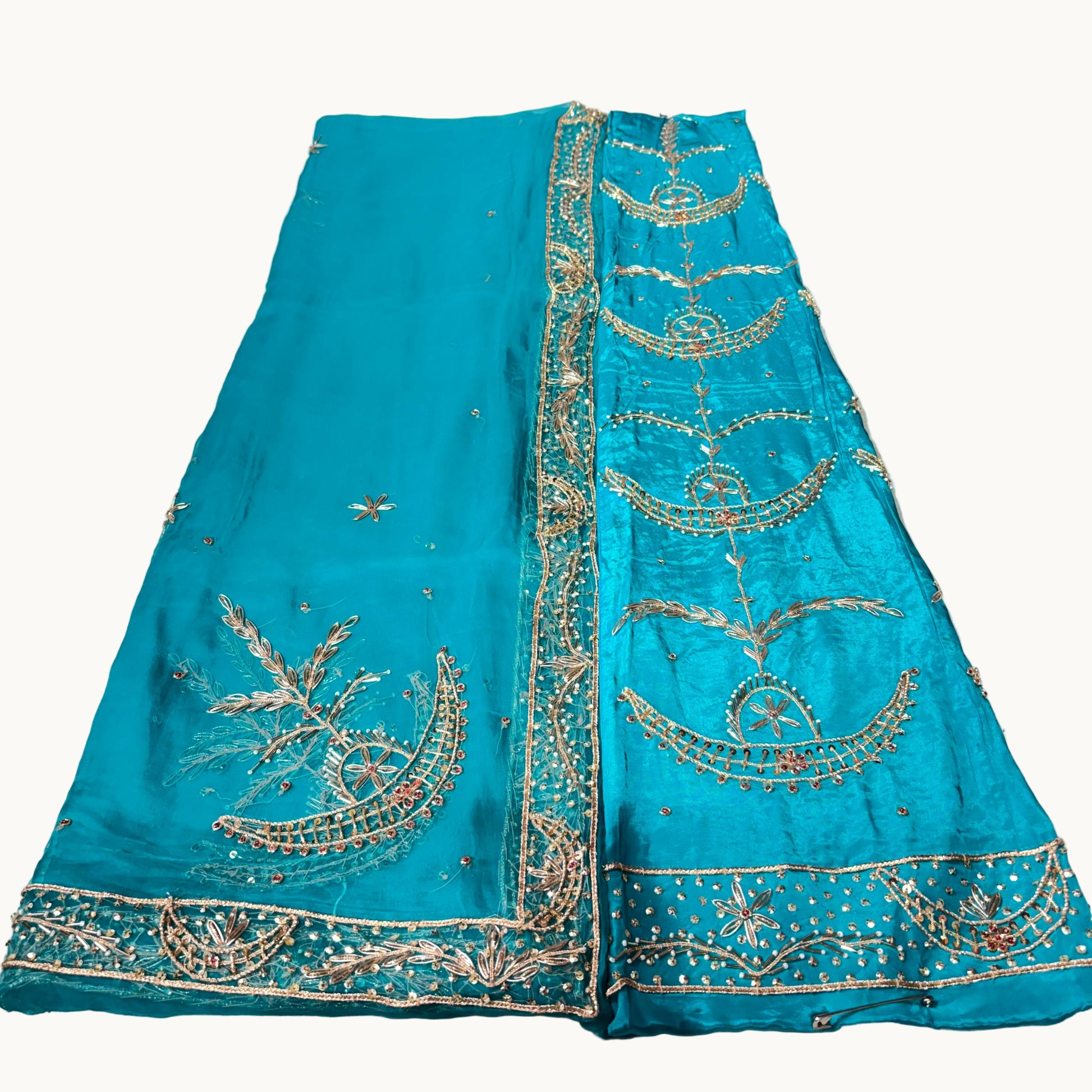 Turquoise fabric with gold embroidery on a white surface
