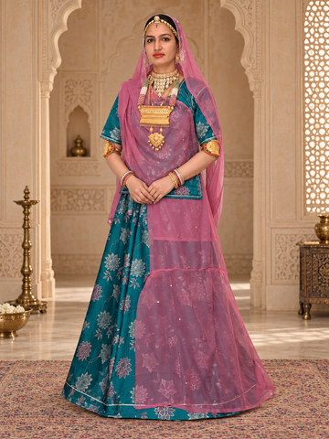A woman models a traditional Indian rajputi poshak outfit in sage green and black with gold embroidery, set against an ornate, historic interior with arches and brass lamps.