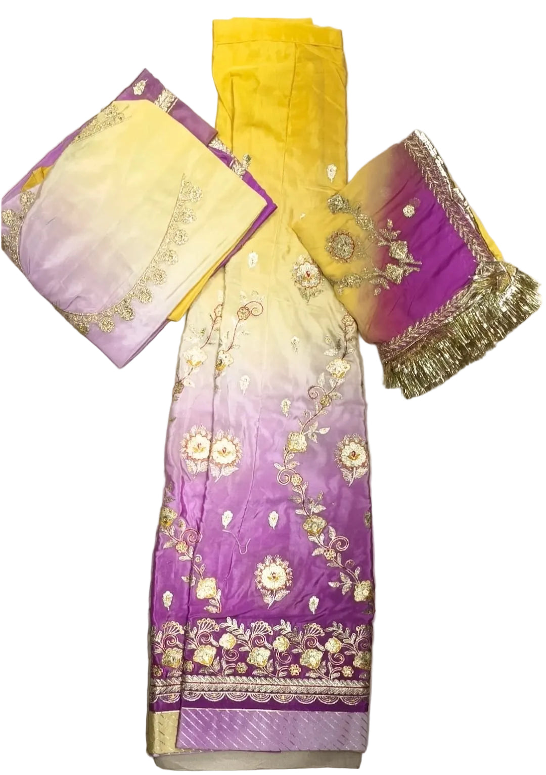 A three-piece traditional Indian salwar suit set laid flat on a white fabric background. The set features a purple and yellow gradient salwar, matching yellow and purple gradient trousers, and a coordinating dupatta with gold floral embroidery and fringe.