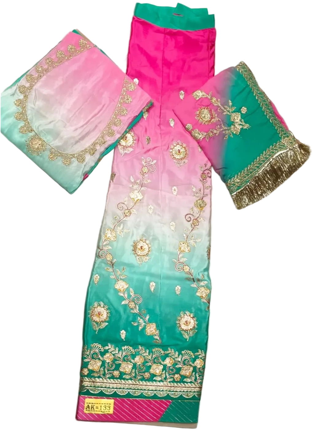 A three-piece traditional Indian salwar suit set laid flat on a light beige fabric background. The set features a pink-to-teal gradient salwar with gold floral embroidery, a matching teal and pink dupatta with gold embroidery and fringe, and solid bright pink trousers.
