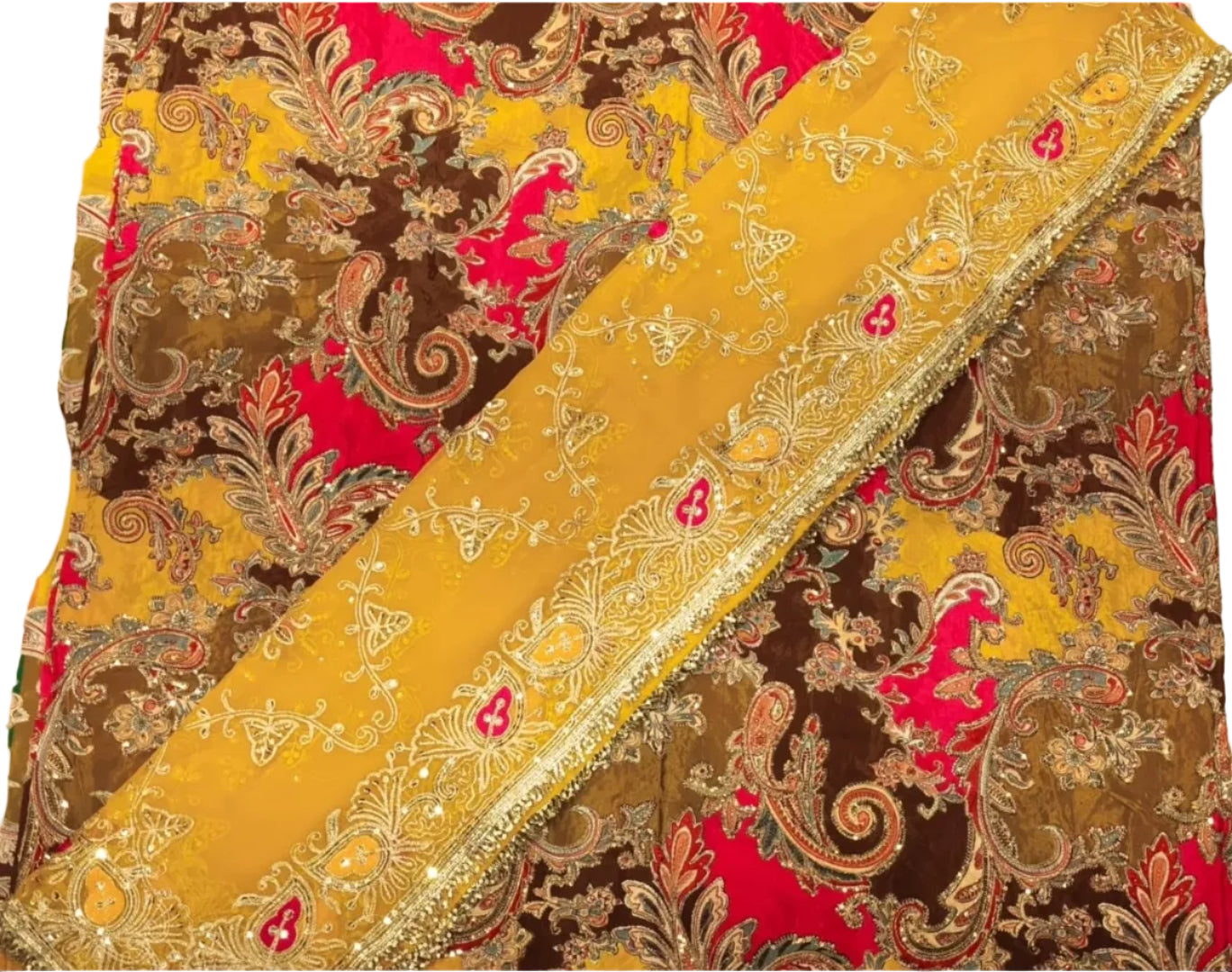 A close-up of a richly patterned fabric, likely a saree or textile, featuring a mustard yellow dupatta draped diagonally over a matching body fabric. The fabric has an intricate paisley and floral pattern in brown, bright pink, and gold zari embroidery.