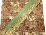 A close-up of a patterned fabric or textile laid flat, featuring an ornate paisley and floral design in brown, beige, and muted green tones, with a wide mint green border running diagonally across the fabric.