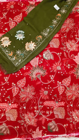 Red floral printed fabric with an olive green embroidered border and matching embroidered fabric piece laid diagonally across the top left.