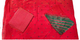 A red fabric garment laid flat on a white surface, with small black dot embellishments, a matching red striped fabric piece, and a green striped fabric piece.