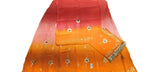 A folded orange and pink gradient fabric, likely a saree or dupatta, featuring small embroidered floral motifs and a decorative border, laid out on a light-colored surface.