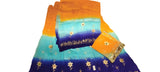 A folded and draped three-piece salwar suit set featuring a vibrant gradient fabric with orange, light blue, and dark blue sections, decorated with white floral embroidery and gold zari borders.