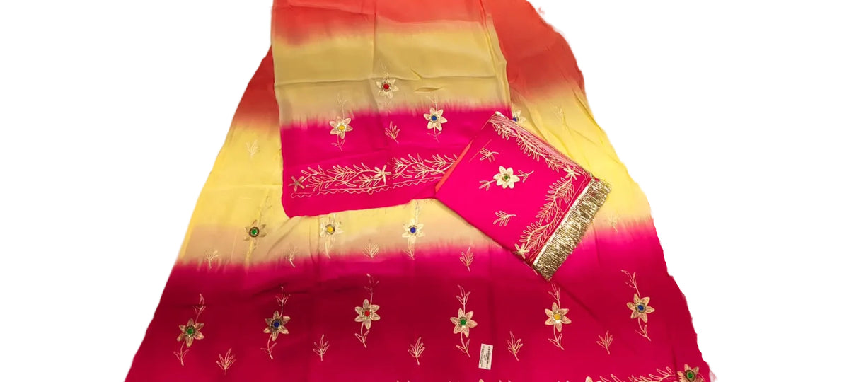 A folded bright pink and yellow gradient fabric with white floral embroidery and a patterned border, laid on a light-colored surface.