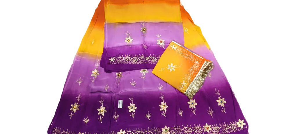 A folded purple and orange gradient fabric garment with gold floral embroidery, shown on a light marble-like surface with a matching orange fabric tag.