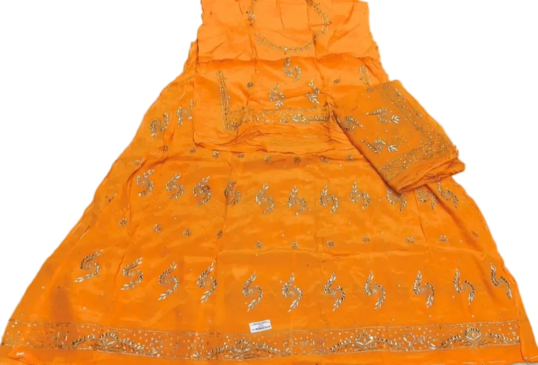 An orange traditional ethnic outfit laid flat on a white sheet, featuring gold embroidery and a matching dupatta.