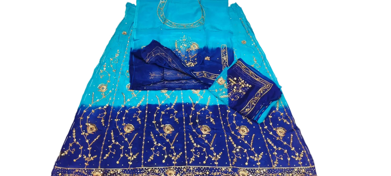 A blue and turquoise gradient ethnic dress with gold embroidery, laid flat on a white fabric surface alongside matching accessories.