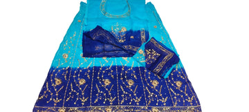 A blue and turquoise gradient ethnic dress with gold embroidery, laid flat on a white fabric surface alongside matching accessories.