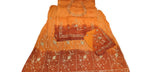 An orange and rust-colored traditional Indian salwar suit set laid out on a white sheet, featuring a kurta with silver mirror work, a matching bottom fabric, and a dupatta.
