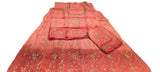 A pink embroidered traditional outfit laid flat on a white sheet, with matching dupatta and folded sleeves. The fabric has gold floral embroidery and metallic embellishments.