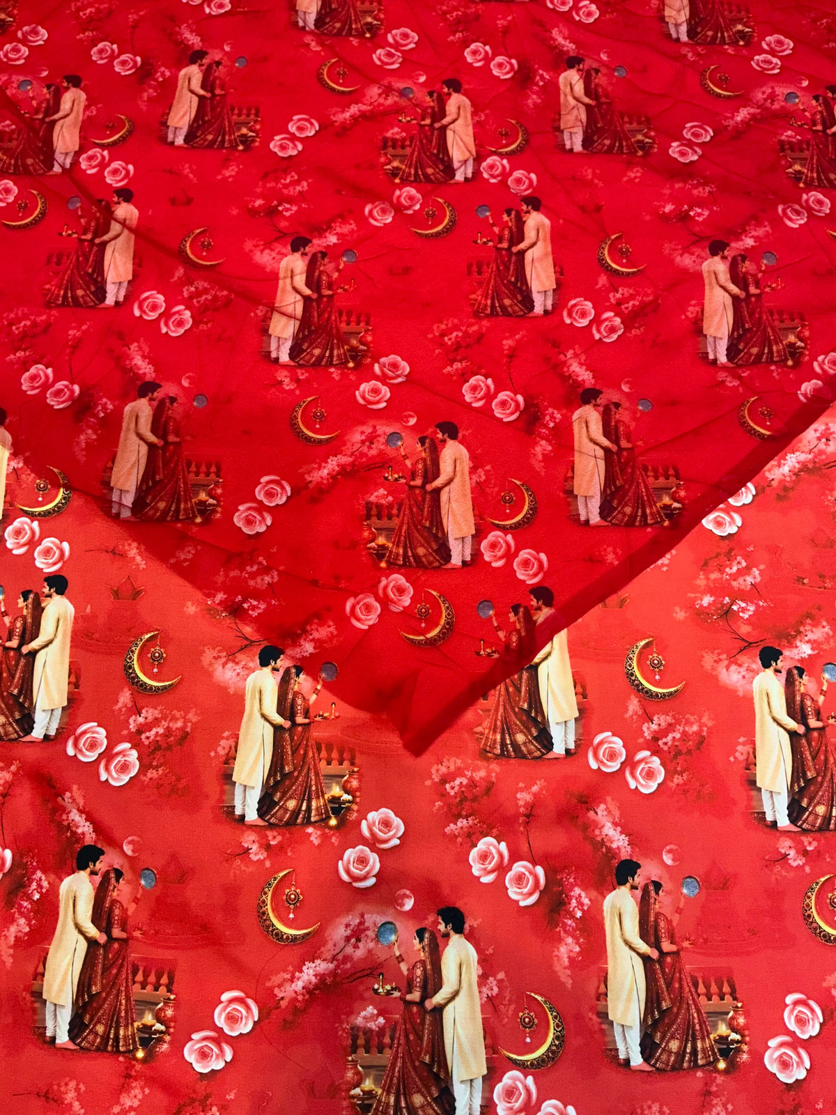 Plain red Rajan odhni with no added work, laid over orange-red BSY poshak fabric printed with couples, crescent moons and pink roses