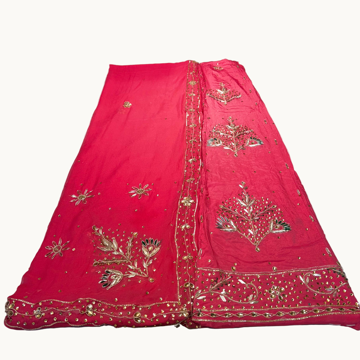 Red embroidered fabric on a white surface with other colorful fabrics in the background.