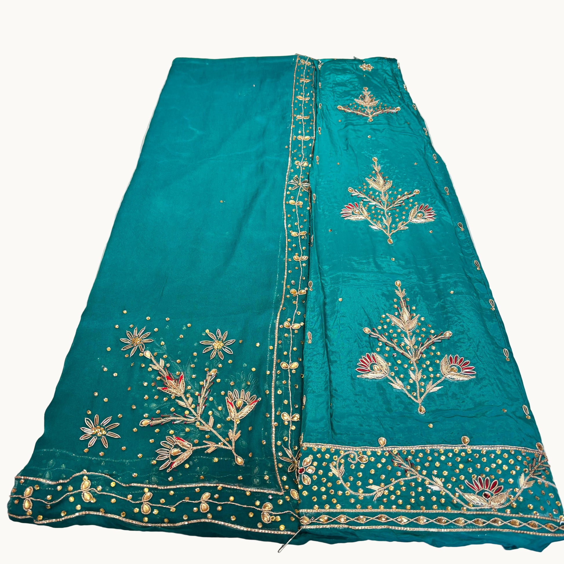 Teal fabric with gold embroidery on a white surface